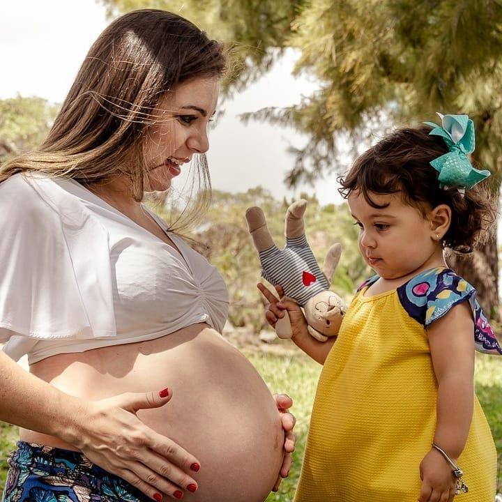 Flávia Maitri grávida ao lado de uma criança, símbolo de maternidade e infância