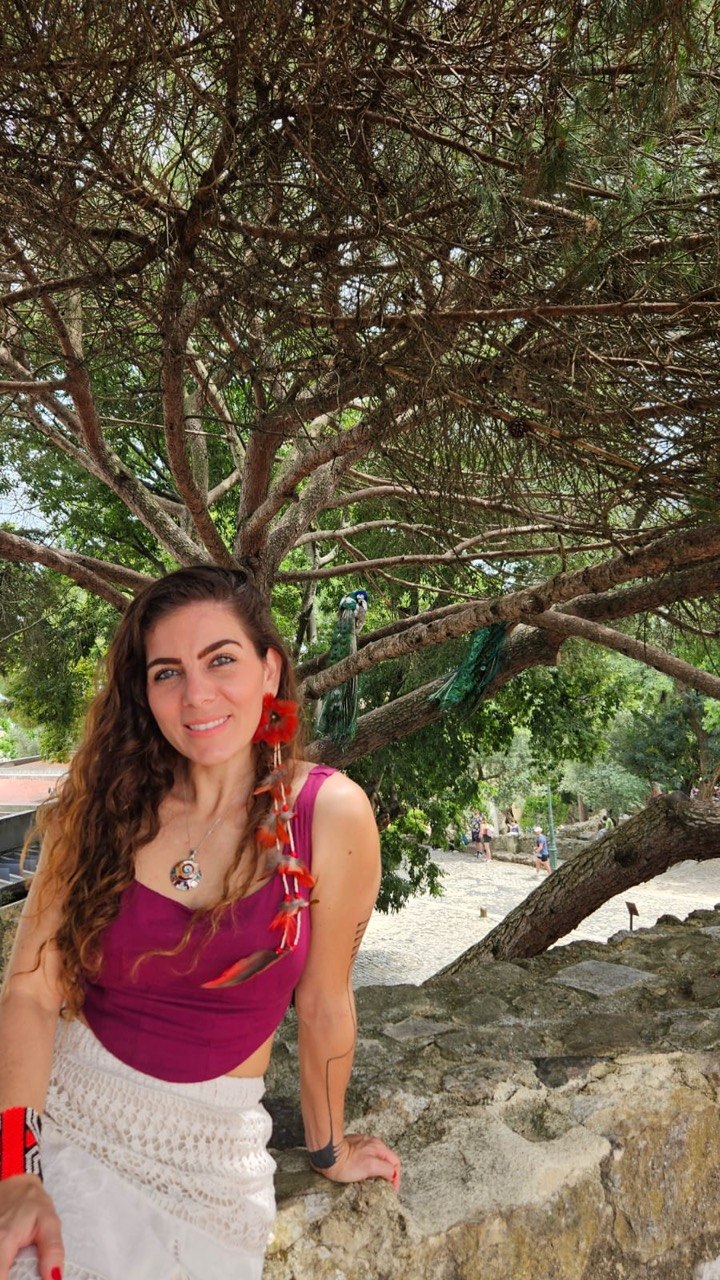 Flávia Maitri ao ar livre sob uma árvore, em ambiente histórico de Minas Gerais